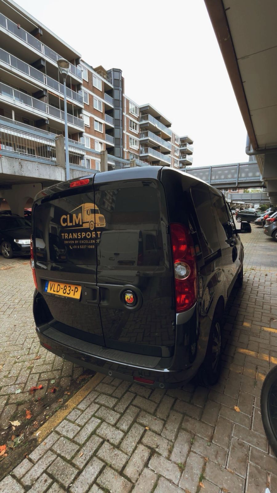 Achterzijde van de zwarte CLM Transport bestelbus met logo